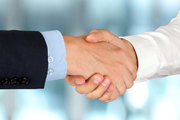 Close-up image of a firm handshake  between two colleagues in office.