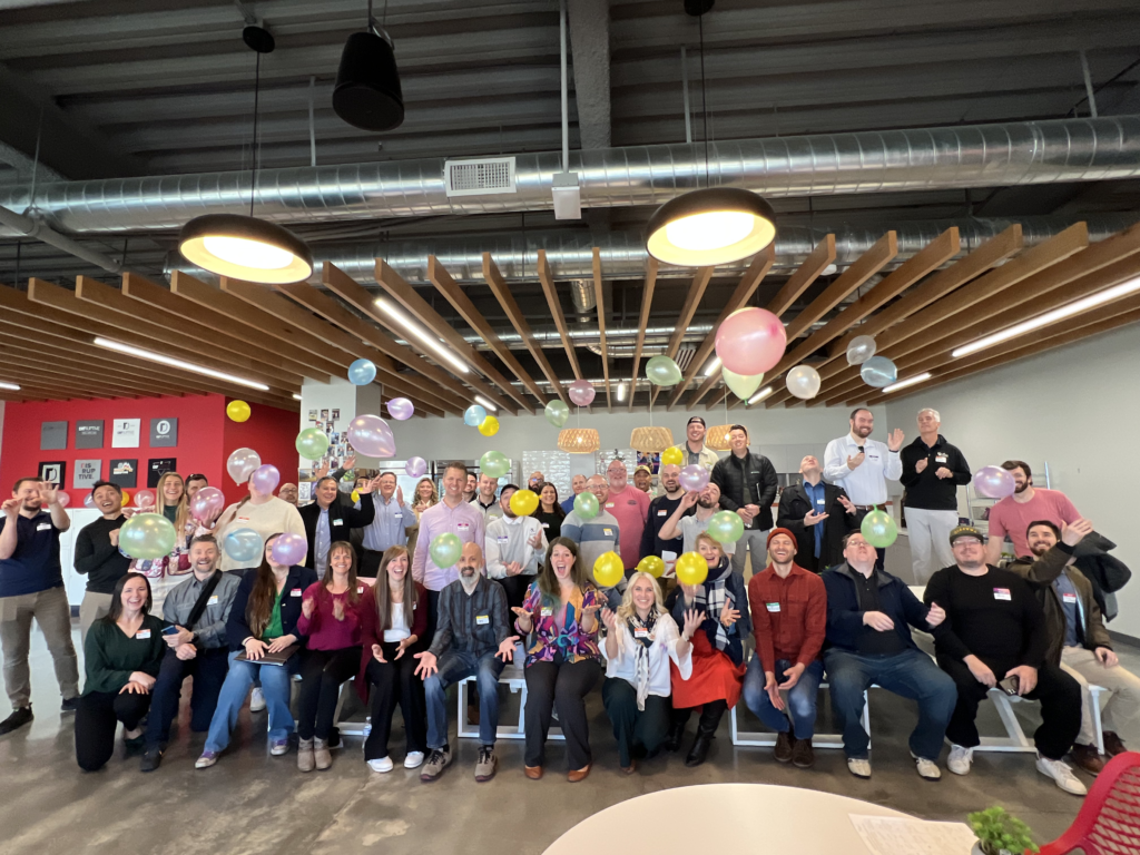 Group photo of Utah Marketing Group members tossing colorful balloons in the air.