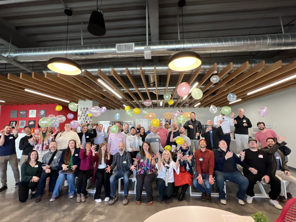Group photo of Utah Marketing Group members tossing colorful balloons in the air.