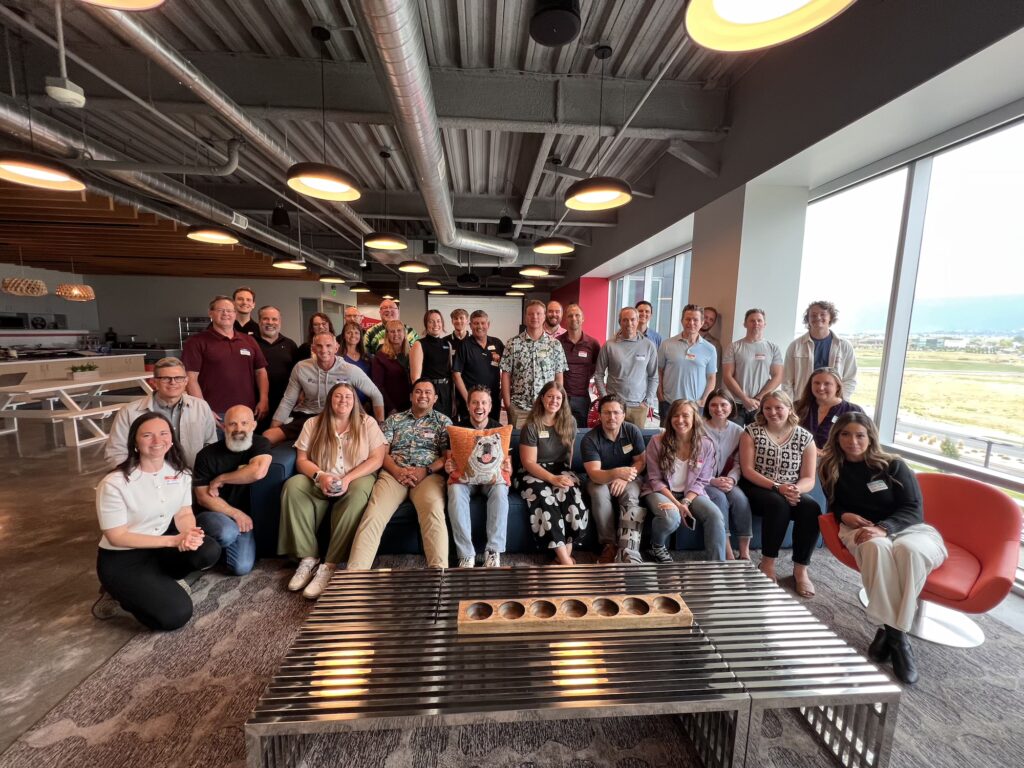 Members of the Utah Marketing Group standing and sitting in a large living area.